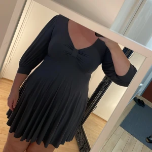 Klänning - Figursmickrande klänning som markerar midjan. Trekvartsarm, v-ringad. Står storlek s men är snarare L