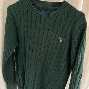 Grön, kabelstickad tröja, gant - Storlek S. Den är i bra skick men förlorat lite färg i kragen och ärmarna. Skick 8/10. Nypris:1400kr. 