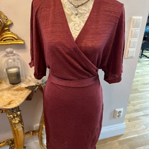 Klänning  - Fin omlottklänning i terracotta färg i stl 38/M från Lindex. Du kan själv justera hur du vill forma klänningen runt din midja vilket gör att klänningen passar för stl som S/M och M/L