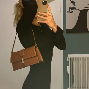 Brun väska  - Använd ca 2 gånger. Skinnimmitation. Perfekt storlek för att få plats med mobil,plånbok osv.
