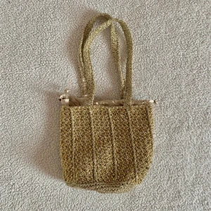 ZARA guldig virkad strandväska med pärlor - Otroligt vacker virkad guldig påsväska från ZARA med guldiga pärlor. Använd en gång, utan anmärkningar. I nyskick. Ordinariepris 399kr.