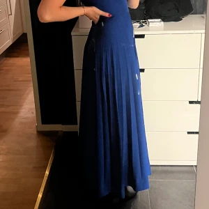 Kornblå långklänning  - Lång kornblå klänning med plisserad kjol och går upp lite i halsen, dragkedja i rygg, fullt fungernade