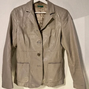 Figurnära skinnjacka/ kava  - Säljer denna snygga beige skinnjacka/ kavaj. Sitter superfint i midjan när den är stängd. Står att storleken är 42 på lappen men skulle säga att den sitter som en 38 - Köpt secondhand  - Äkta läder Fler bilder kan fås på begäran 