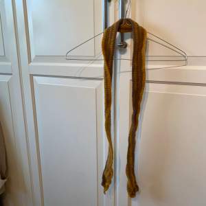 Smal stickad halsduk som är 145cm lång