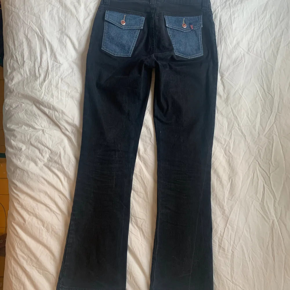 Skit coola svarta Lågmidjade jeans med blåa patches och blåa bakfickor.  Innerbenslängd: 81cm Midjemått runt hela: 77cm  Fråga för fler bilder . Jeans & Byxor.