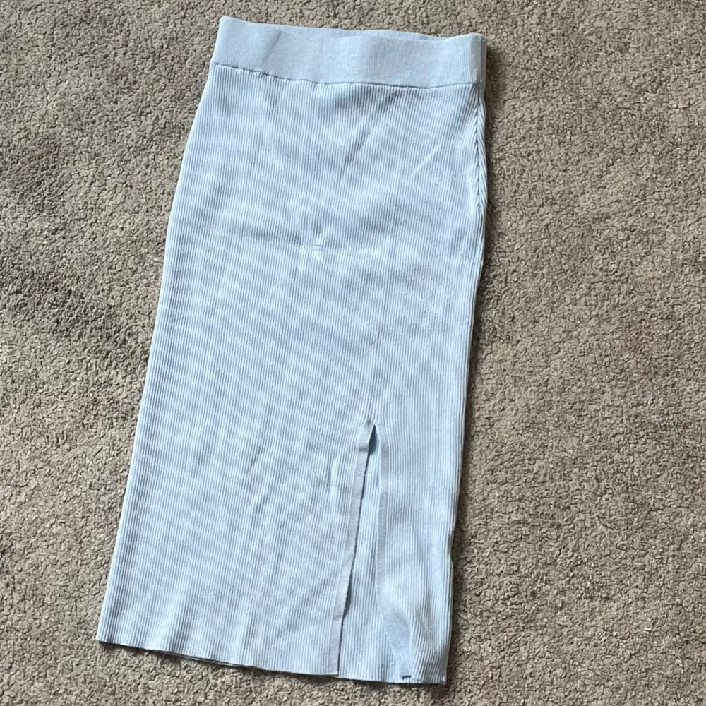 En blå ribbad kjol med liten slits som används ett fåtal gånger . Kjolar.