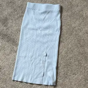 En blå ribbad kjol med liten slits som används ett fåtal gånger 
