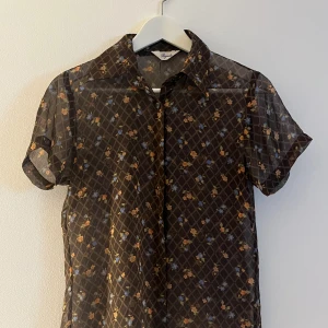70s skjorta - Blommig skjorta i lite 70 tals-stuk! Materialet är i mesh/chiffong.  Säljer då den tyvärr inte kommit till användning.  Bra skick!