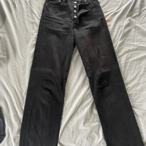 Svarta Levis jeans - Svarta jeans från Levis i fint kvalité, modell ribcage straight. Storlek 24 då midjemått är 31cm och innerbenslängd är 65cm
