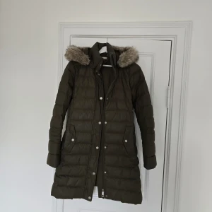 Tommy Hilfigher dunjacka lång  - Bra skick, dock saknas flärpen där bak. Mörkgrön stl xs, men funkar även som en stl s. Nypris 2300 kr. 