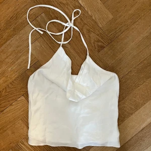 Zara festtopp - Snygg festtopp från zara som knyts i nacken och har öppen rygg. Aldrig använd men köptes med sminkmärke som ej syns när man har på sig den, går bort i tvätt. Säljes pga förliten