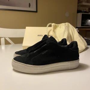 Axel Arigato  - Nypris: 2650 kr Vid köp av skorna får du även med kartongen och dustbag.  Guldfärgade ”axel arigato” trycket i skorna och utanpå åkte bort bara en månad efter jag köpte de.  Mockan går att putsa upp mer fint, men hade inget verktyg för det hemma. 