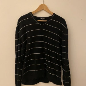 Svart/vit randig tröja - Jättesnygg svart v-ringad långärmad med vita ränder! Har ett litet hål på axeln. Storlek L men funkar även som oversize. Tröjan är 100% bomull💕