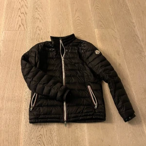 Moncler jacka  - Moncler jacka.  Jackan har ett hål där bak (bild 2) det går att laga annars är det inga problem med den. Jackan är självklart äkta. Jag skulle säga att den passar S-M  Storlekarna är lite svåra att förstå. Tveka inte på att höra av dig vid frågor!