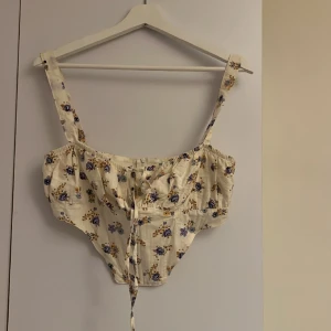 Väldigt fin sommartopp - Mycket fin sommartopp i blommigt mönster. Topp med korsettdrag. Aldrig använd 