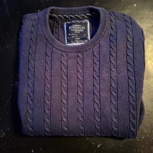 Mörkblå kabelstickad tröja från märket Bondelid. Storlek L, plagget har ett bra skick.