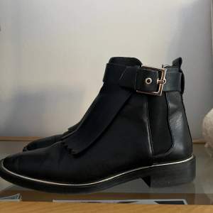 Snygga boots med tuffa detaljer - från Zara i läder, Använda men ok skick, anmärkning: bältenas läder har lossnat lite från sitt undermaterial, kan lätt limmas. 