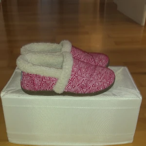 Tofflor - Skorna är röda vita och på insidan är dom fluffiga. Det kommer från märket Toms. Och det är storlek 25-27