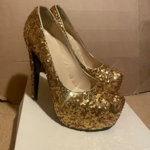 Guld glittriga klackskor - Glittriga Guld klackskor.  Högklack, endast testade. Storlek 38