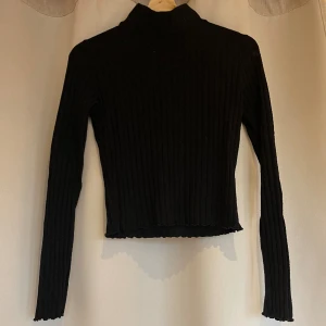 Svart långärmad polotröja  - Svart långärmad polotröja från Ginatricot med lite volang detalj ned till och i ärmarna (se 2:a bilden). Strl S