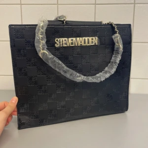 Steve Madden Handväska - Helt ny oanvänd handväska från Steve Madden. Prislapp kvar. Svart med gulddetaljer