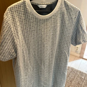 Vit och svart mönstrad t-shirt från Samsøe Samsøe  - En vit t-shirt från Samsøe Samsøe med ett subtilt svart mönster. T-shirten har korta ärmar och en rund halsringning.