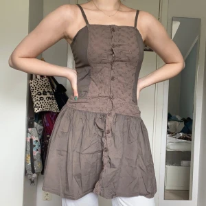 Ljusbrun miniklänning i bomull - Miniklänning från Orsay med smock och knäppning framtill. Tunna justerbara band, storlek 36 men kan passa 38 också.