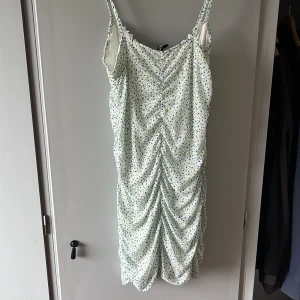 Klänning - Nyskick aldrig använt ljus grön ljus blå blommor med vit emellan tajt fit men skönt material likt silke säljer billigt eftersom den aldrig använts.