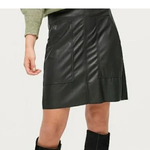 Kjol skinnimitation  - Svart oanvänd kjol i skinnimitation I strl 38. Kan tvättas i 40 grader. Katt finns I hemmet