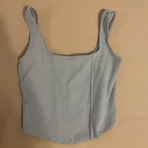 Ljusgrå korsett från Gina Tricot - En ljusgrå topp från Gina Tricot. Korsetten har breda axelband och en enkel design utan mönster eller detaljer. Skriv gärna om ni har frågor 💕