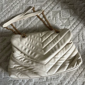 Vit ”läder” väska  - Jätte fin och rymlig väska med guldkedja. Köpt för några år sen men använd ca 3 tillfällen. 