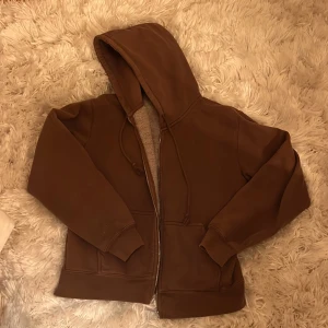 Brun zip-up hoodie  - En brun zipup tröja från Brandy Melville. Den är fortfarande i gott skick och känns bra på. Storleken är onesize, men passar bäst på XS-M. 