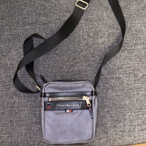 Tommy Hilfiger väska - Mindre axelväska, med en innerficka med dragkedja. En korthållare på baksidan och ett vanligt fack på framsidan med dragkedja. Använd men i bra skick.