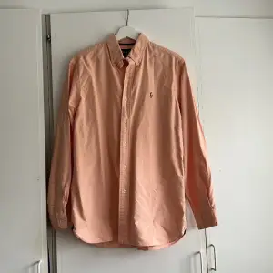 Skjorta från Ralph Lauren i 100% bomull. En superfin aprikos färg, perfekt nu till våren/sommaren! Använd men i toppenskick helt utan anmärkningar. Storlek M :)