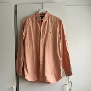 Ralph lauren skjorta - Skjorta från Ralph Lauren i 100% bomull. En superfin aprikos färg, perfekt nu till våren/sommaren! Använd men i toppenskick helt utan anmärkningar. Storlek M :)