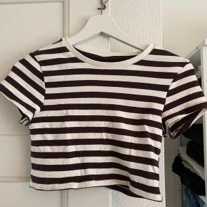 Randig croppad topp från Gina tricot  - Använd ett fåtal gånger och är i bra skick.  Den är brun/vit randig från Gina tricot  Storlek M Köparen står för frakten 