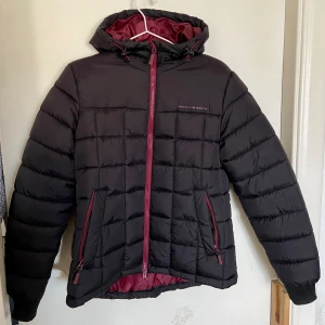 Vinterjacka - Svart vinterjacka med vinröda/mörk rosa detaljer, köpt hos Engelsons. Använd ca 1 gång. Säljer för att den inte kommer till användning. Damstorlek 38. 