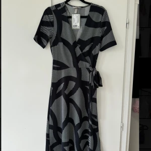 Midiklänning omlott  - En midi lång klänning med omlott från H&M. Nyskick aldrig använd. Prislapp kvar! Storlek XS. Nypris: 299kr.