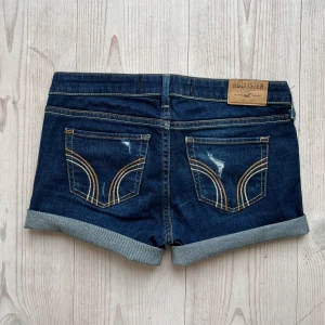 Lågmidjade blå jeansshorts från Hollister - Mörkblå lågmidjade jeansshorts från Hollister som jag har gjort om från ett par byxor. Storlek W28 L33 men små i storleken så skulle säga att de passar XS/S. Tvärs över midjan är det 39 cm. Använd gärna köp nu!