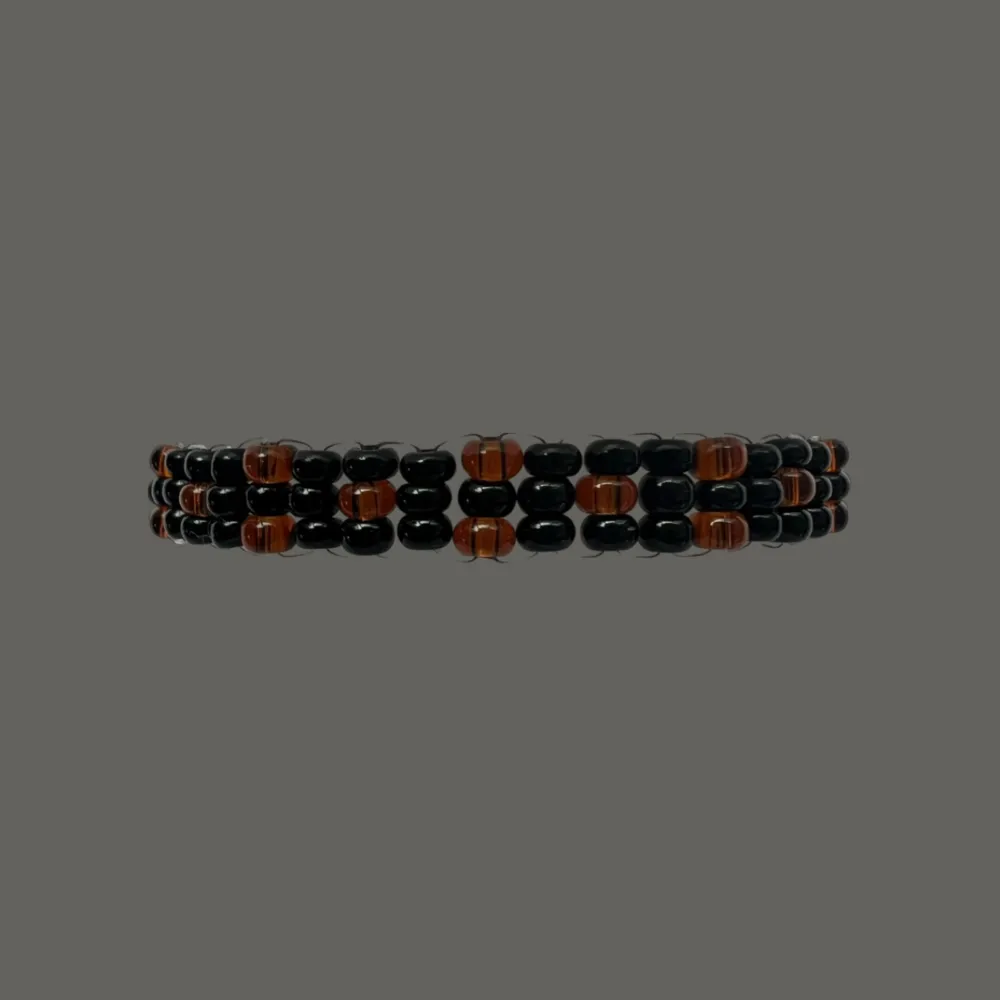 Hephaestus II Orange är ett snyggt armband uppbyggt av mörkorangea och svarta rocaillespärlor. Armbandet har en omkrets på cirka 18 cm men är töjbart.. Accessoarer.