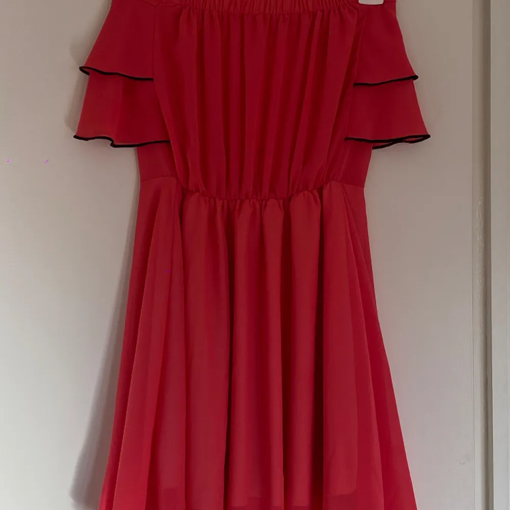 Så fin volangklänning, en kort klänning med lite svarat detaljer. Seg lite ut som att klännign är väldigt röd men är mer åt rosa och orange hållet.. Klänningar.