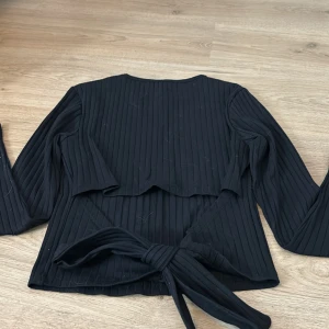 Tröja  - En svart tröja me en öppen rygg med rosett! 