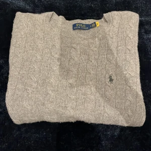 Kabelstickad Kashmir ralph lauren tröja - En grå kabelstickad Kashmir Ralph Lauren tröja. Sparsamt använd och mycket fin. Nypris är ca 3000kr men jag säljer för 1899kr. Eventuella byten kan tas
