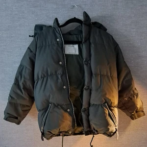 En Grön Polarn O Pyret dunjacka - En varm, behaglig och rörlig jacka. Går att fästa och ta av luvan med hjälp utav knappar (ses vid bilder) drag kedja till att stänga jackan finns också möjlighet till att knäppa fast den.