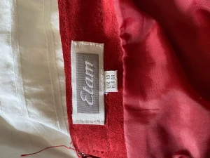 Röd Mocka kjol - Snygg, söt, röd, lång mockakjol. Storlek 38/ S-M. Midjemått: 76 cm runt om. Längd 60 cm. Har en dragkedja där bak. Retro vibe. Det enda tecknet på användning är vid dragkedjans ände. Kontakta för fler frågor eller bilder.