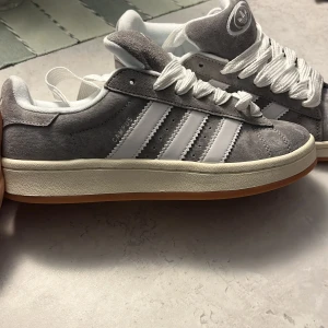 Adidas Campus 00s - Gråa adidas campus i 39 och 1/3. De var för små för mig. Helt nya aldrig använda. Köpte dom på plick av en tjej som också endast testat. Hör av er vid frågor! Och pris går att diskutera. 