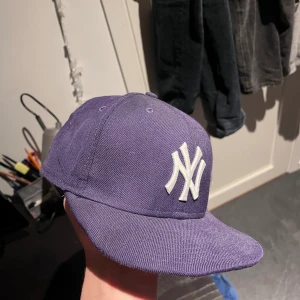 New Era yankees keps - bekväm new era keps i färgen lila som jag haft i ett par år nu, inte använd så mycket pågrund av att den inte passar längre. storlek 7 1/8. Skicket är bra men såklart inte i nyskick
