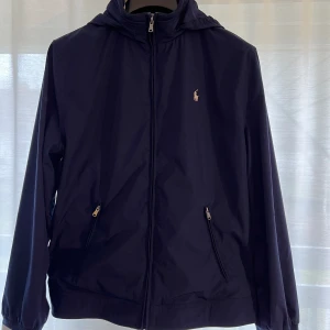Ralph Lauren jacka - Säljer en Ralph Lauren windbreaker i storlek barn XL vilket motsvarar S/M i vanlig storlek. Luvan går att vika in. Perfekt skick, nu tvättad.