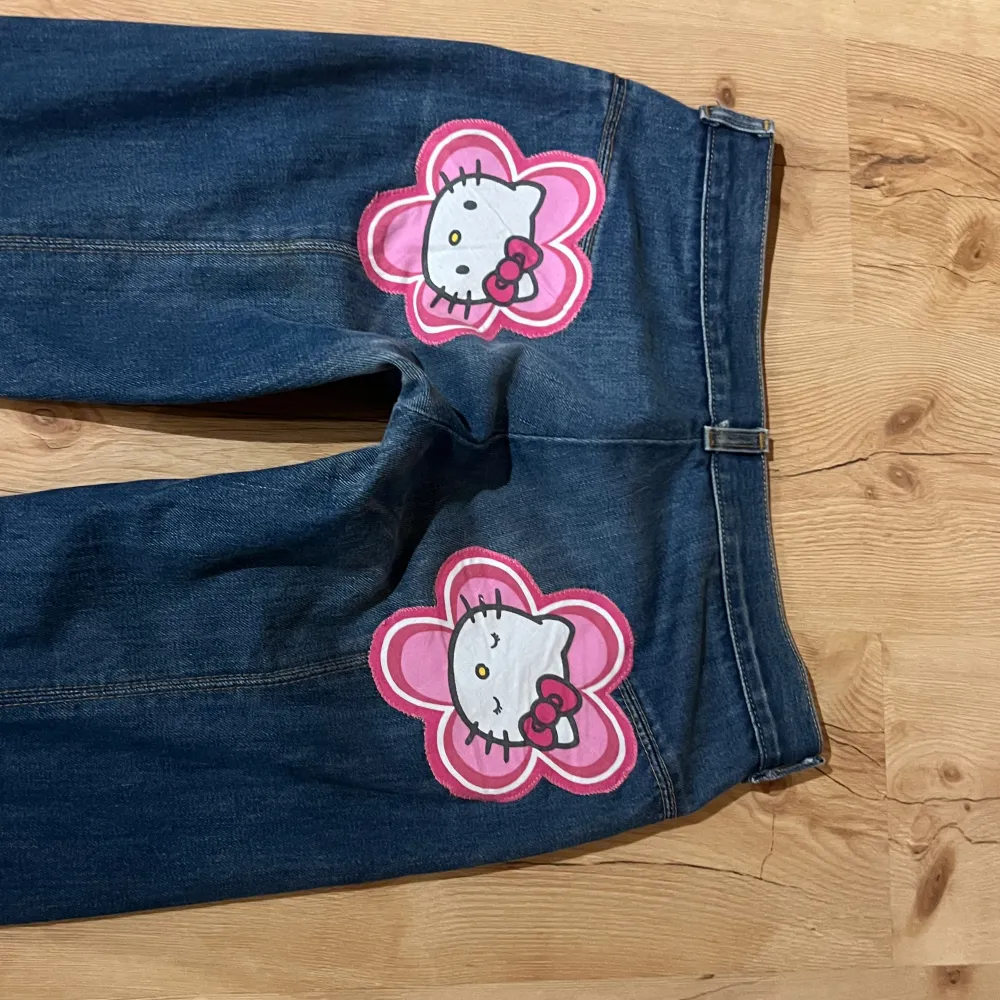 Säljer dessa as snygga vida och lågmidjade  jeansen med hello kitty motiv på rumpen!! 42 rakt över höfterna och 82 cm innerbenslängd ❤️. Jeans & Byxor.