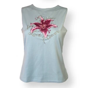 Coconutgirl Linne  - Ett snyggt linne okej skick, se sista bilden för ett litet hål. Glittrig silver text med en hibiskusblomma. Från Miss Ewing, storlek L. Dockan använder XS. MÅTT: Axel till axel 30cm, armhåla till armhåla 42cm & längd 54cm.